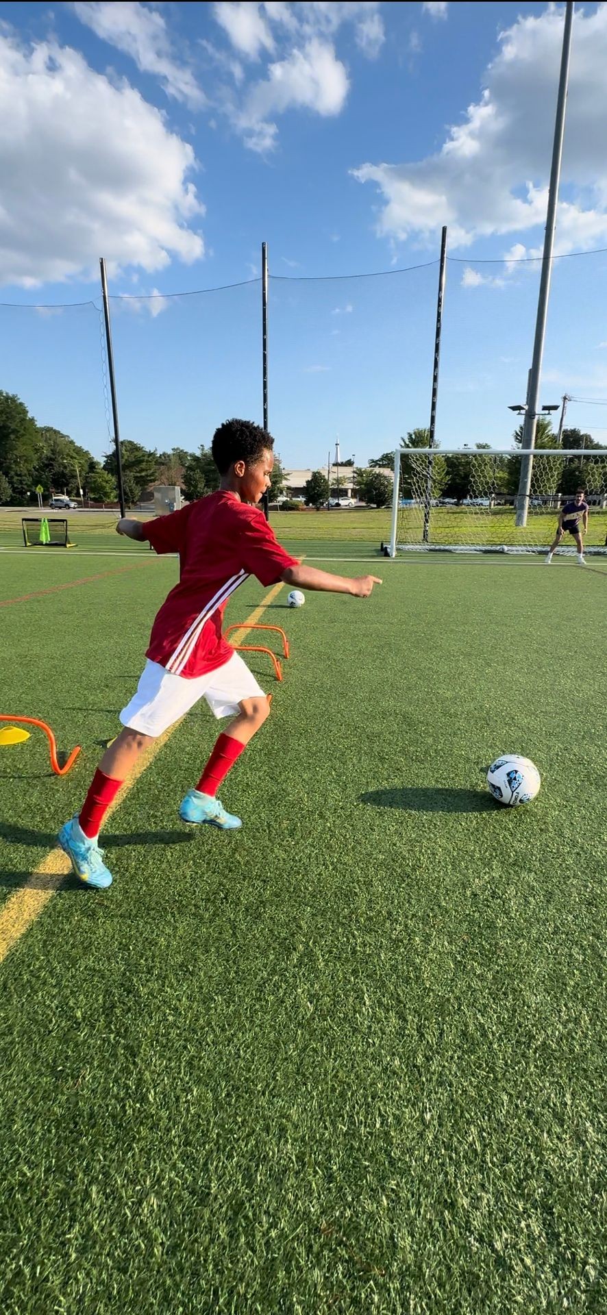 Youth soccer player running towards ball on field during practice.